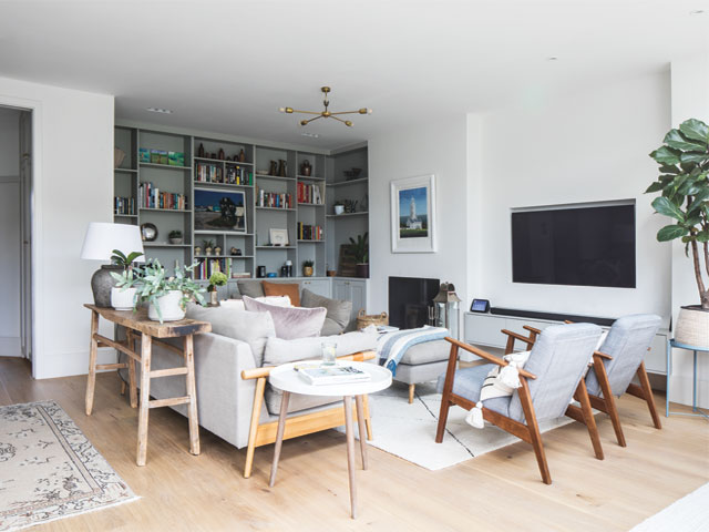 the living area in an open plan kitchen, dining and living space with built in wall-to-wall shelving